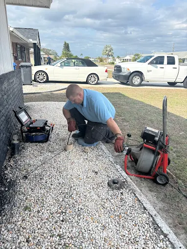 Plumber using drain snake at sewer cleanout - Kabam Plumbing drain cleaning service